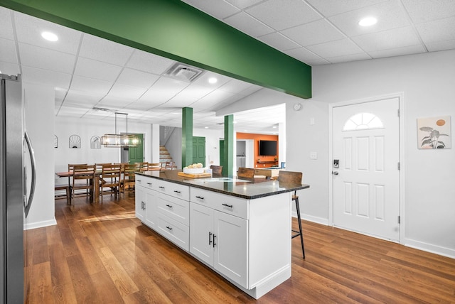 kitchen with white cabinetry, stainless steel fridge, a breakfast bar area, pendant lighting, and a center island