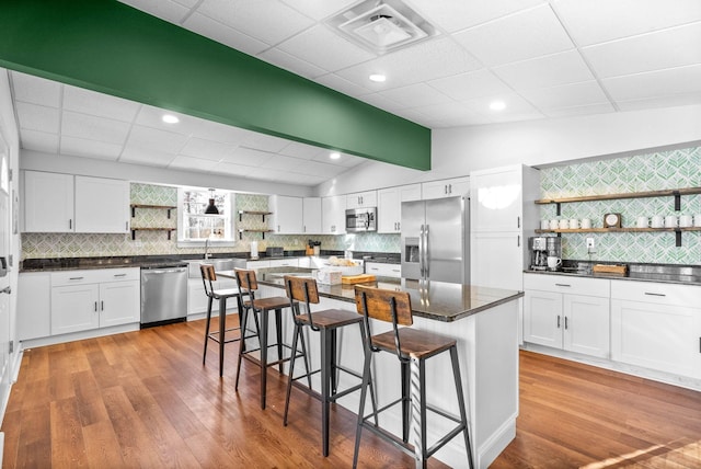 kitchen with vaulted ceiling, a kitchen island, a breakfast bar area, stainless steel appliances, and white cabinets