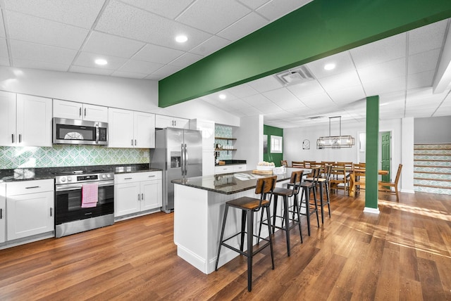 kitchen with stainless steel appliances, a kitchen breakfast bar, vaulted ceiling, a kitchen island, and white cabinets