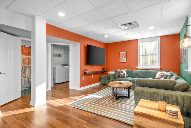 living room with separate washer and dryer, a drop ceiling, and hardwood / wood-style floors