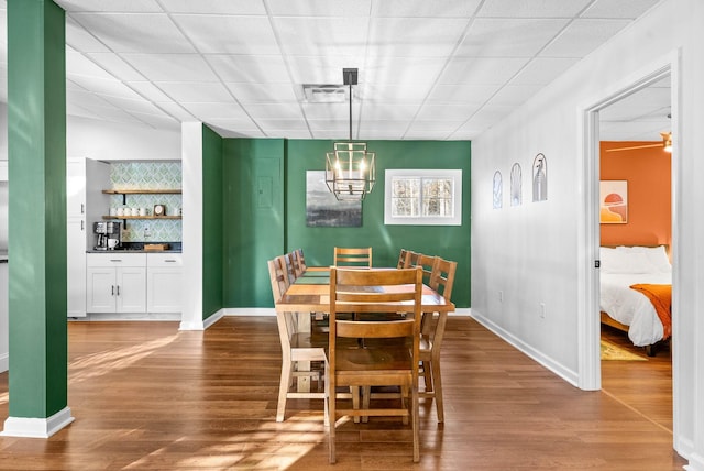 dining space featuring a paneled ceiling, an inviting chandelier, bar, and hardwood / wood-style floors