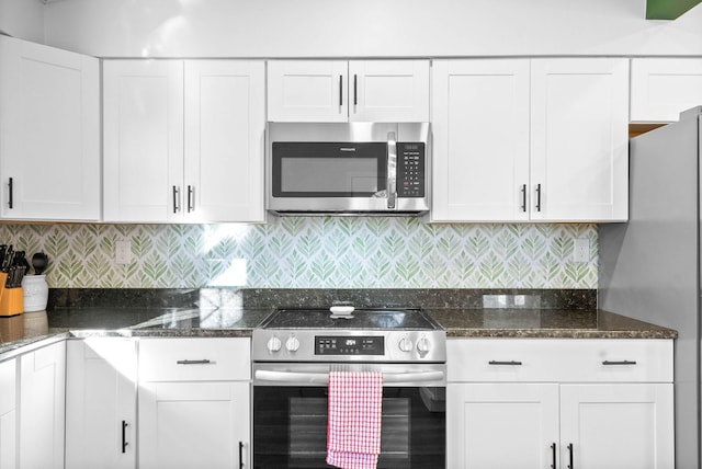 kitchen with stainless steel appliances, backsplash, white cabinetry, and dark stone counters