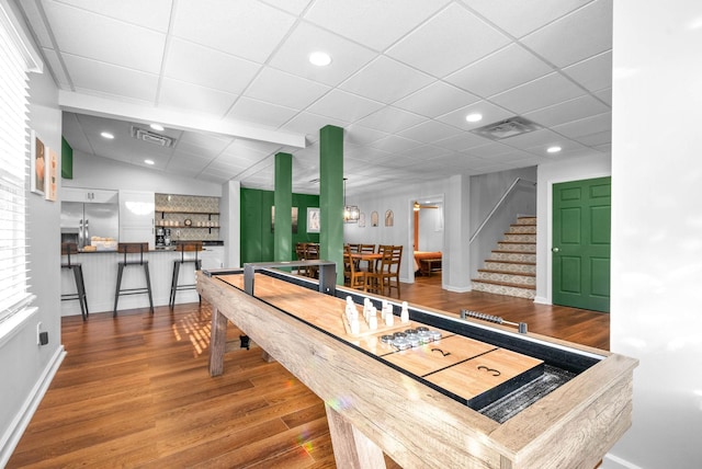 recreation room with vaulted ceiling, indoor bar, and hardwood / wood-style flooring