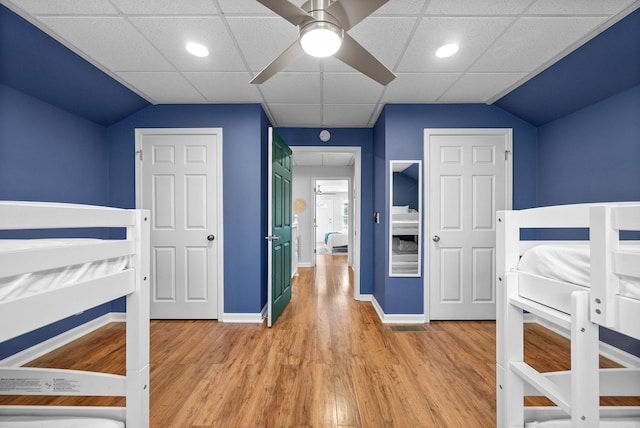 unfurnished bedroom with ceiling fan, hardwood / wood-style floors, a paneled ceiling, and lofted ceiling