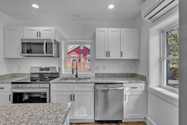 kitchen with sink, white cabinetry, a wall unit AC, and stainless steel appliances