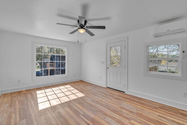 spare room with ceiling fan, light wood-type flooring, plenty of natural light, and a wall unit AC