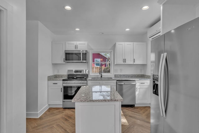 kitchen featuring stainless steel appliances, white cabinets, an AC wall unit, and sink