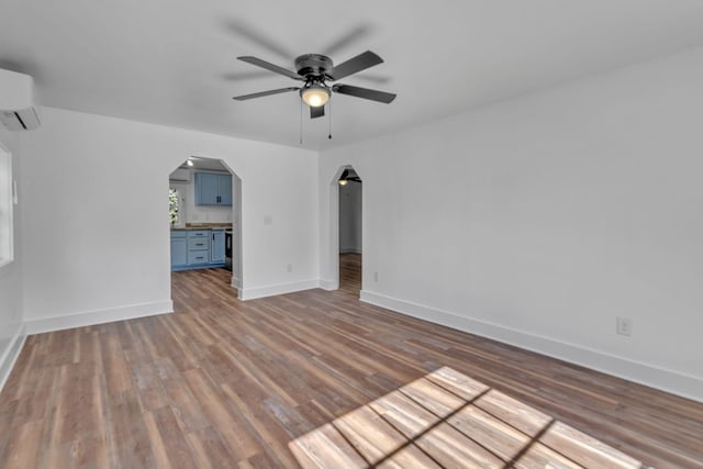 interior space with dark wood-type flooring, ceiling fan, and an AC wall unit