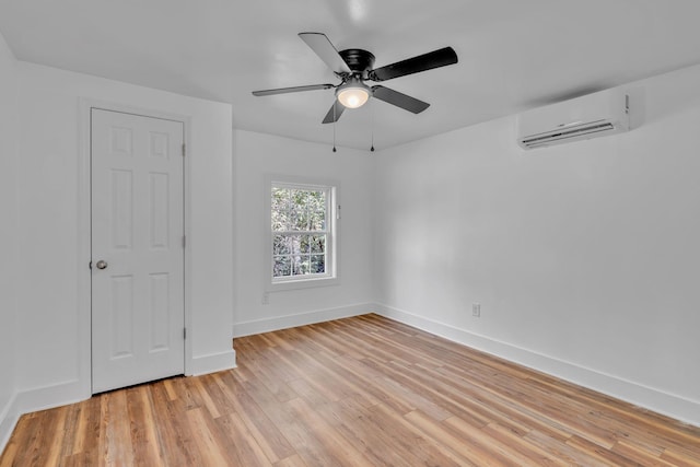 spare room with ceiling fan, light hardwood / wood-style flooring, and a wall mounted air conditioner