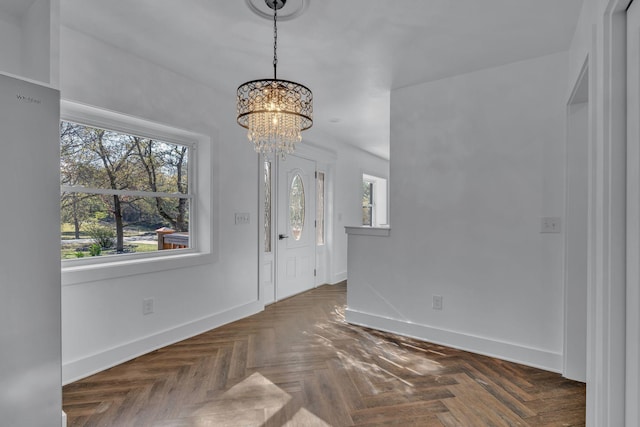 entrance foyer with a chandelier, dark parquet flooring, and plenty of natural light