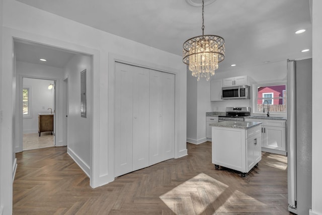 kitchen featuring white cabinetry, appliances with stainless steel finishes, parquet floors, and hanging light fixtures