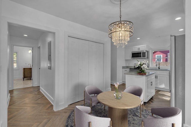 dining area with an inviting chandelier, parquet floors, and sink