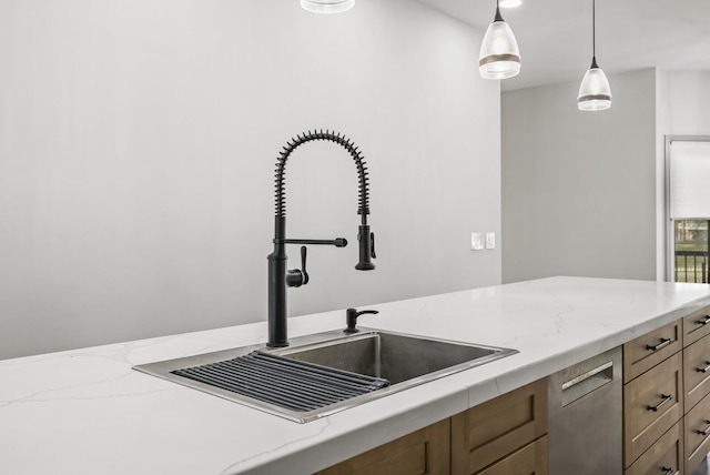 kitchen featuring pendant lighting, sink, light stone counters, and dishwasher