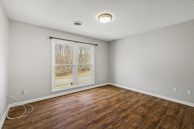 empty room featuring a textured ceiling and dark hardwood / wood-style flooring