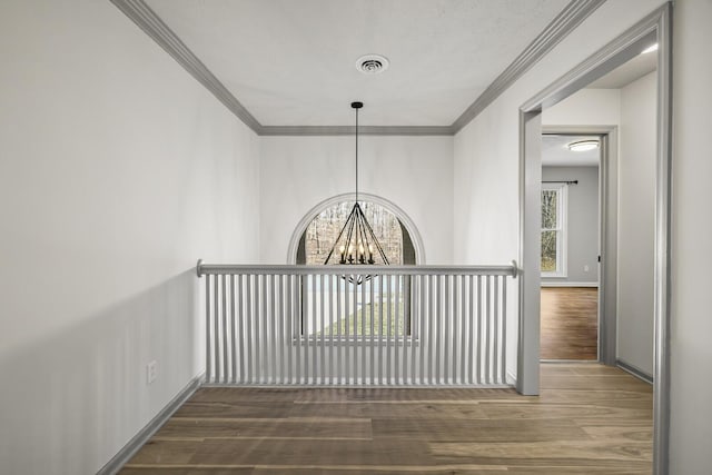 corridor with an inviting chandelier, crown molding, and dark hardwood / wood-style flooring