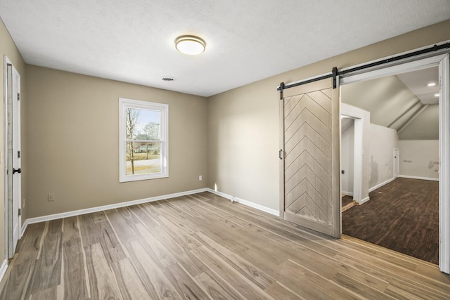 interior space with a barn door, light hardwood / wood-style floors, and a textured ceiling