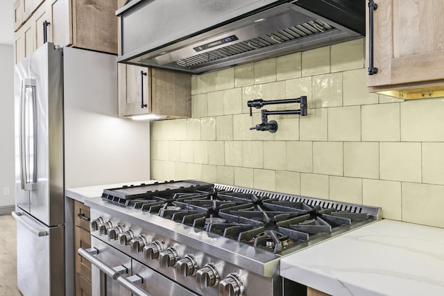 kitchen featuring premium range hood, light brown cabinets, appliances with stainless steel finishes, light stone countertops, and decorative backsplash