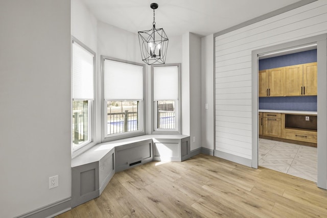 unfurnished dining area featuring a chandelier and light wood-type flooring