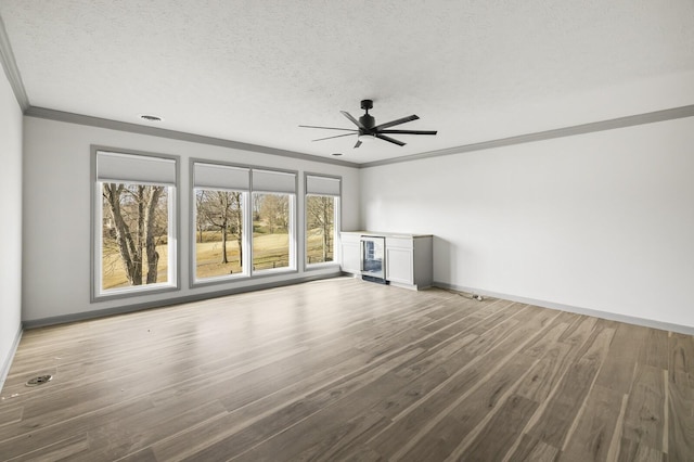 unfurnished living room with hardwood / wood-style flooring, beverage cooler, a textured ceiling, and crown molding