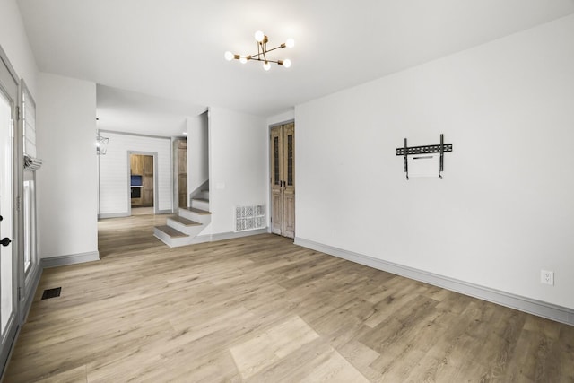 unfurnished room featuring an inviting chandelier and light wood-type flooring