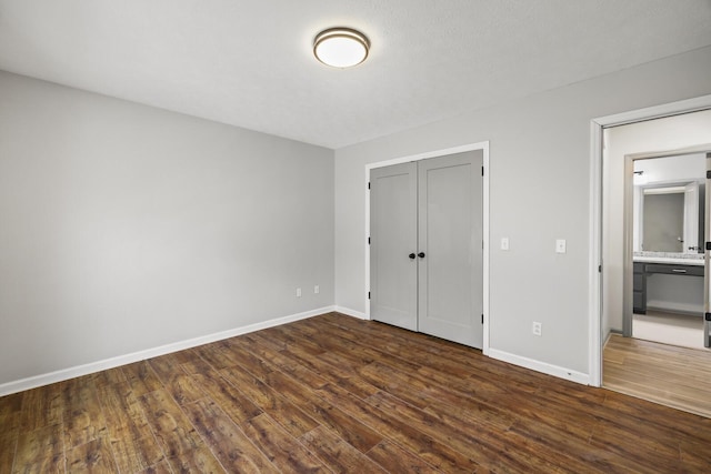 unfurnished bedroom featuring dark wood-type flooring, connected bathroom, and a closet