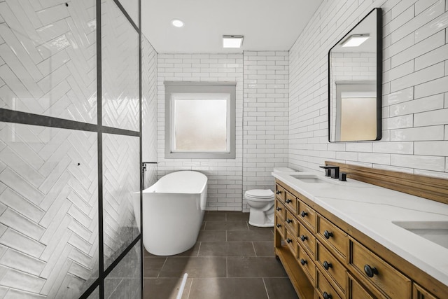 bathroom with tile walls, a bathtub, vanity, toilet, and tile patterned floors