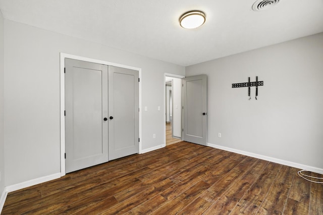 unfurnished bedroom with dark hardwood / wood-style floors and a closet