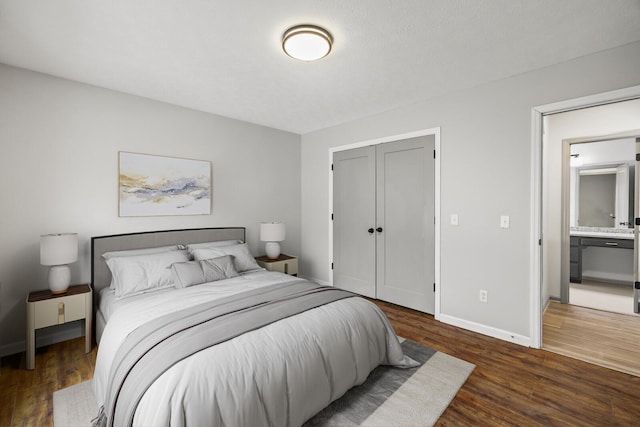 bedroom featuring ensuite bathroom, dark hardwood / wood-style floors, and a closet