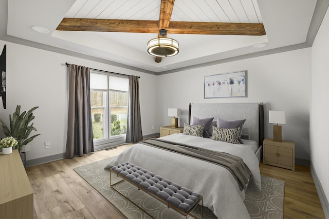 bedroom featuring light hardwood / wood-style floors and a tray ceiling