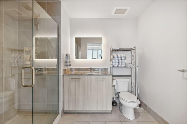 bathroom featuring toilet, tile patterned flooring, a shower with door, and vanity