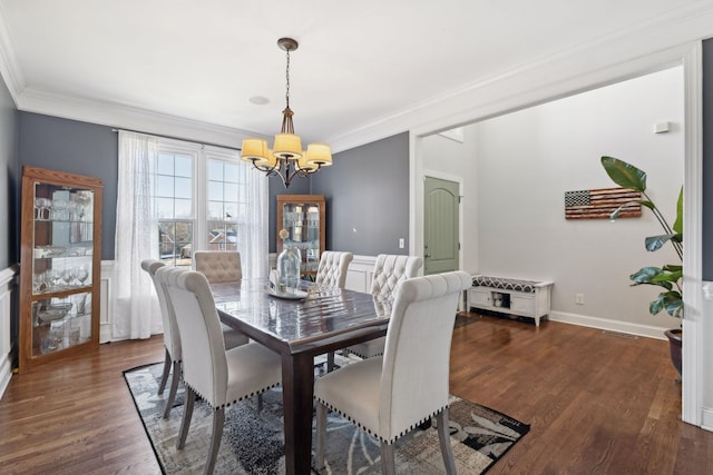 dining area featuring dark hardwood / wood-style flooring, crown molding, and a notable chandelier