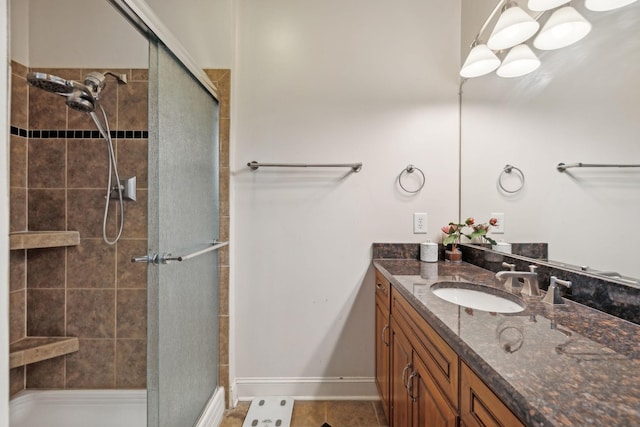 bathroom with a shower with shower door, vanity, and tile patterned flooring