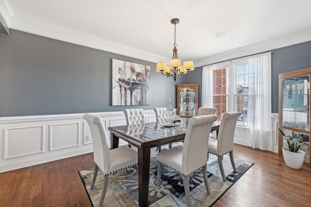 dining room with dark wood-type flooring, crown molding, and a chandelier