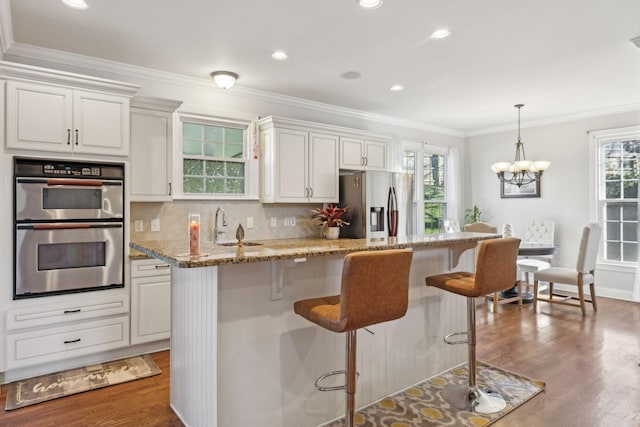 kitchen featuring light stone countertops, crown molding, white cabinets, and stainless steel appliances