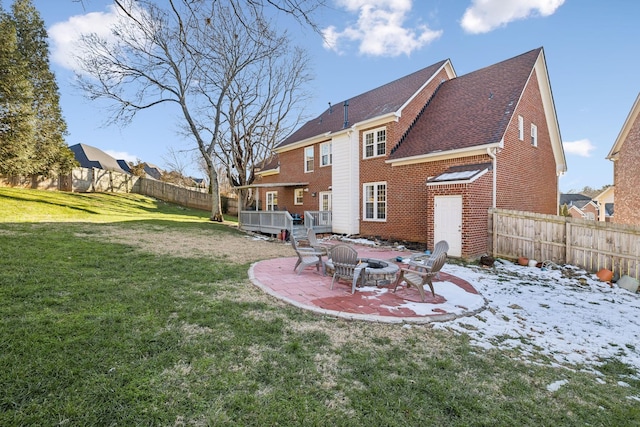 rear view of house with a deck, an outdoor fire pit, a lawn, and a patio