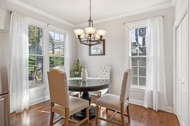 dining space with dark wood-type flooring, crown molding, and a notable chandelier