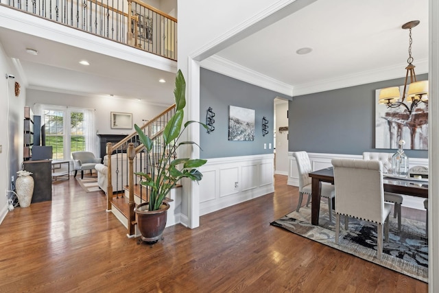 dining area with dark wood-type flooring, ornamental molding, and a chandelier