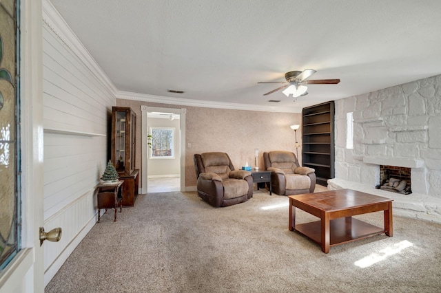 living room with ceiling fan, carpet, crown molding, and a fireplace