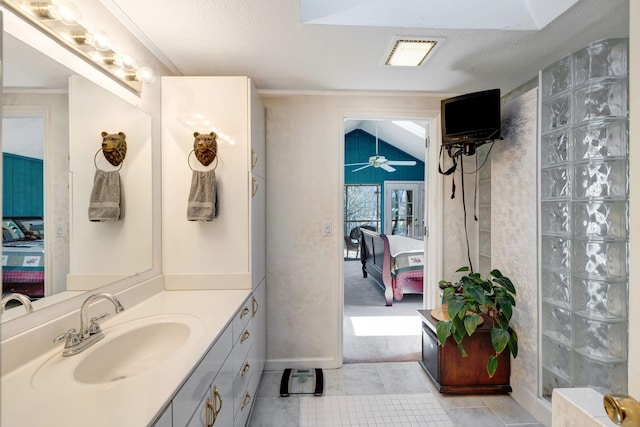 bathroom featuring ceiling fan, vanity, vaulted ceiling, a textured ceiling, and ornamental molding