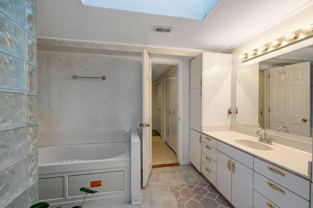 bathroom with a textured ceiling, a washtub, and vanity