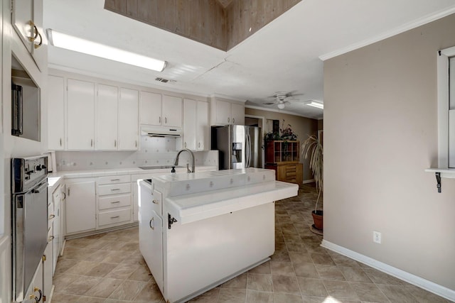 kitchen featuring a kitchen island with sink, decorative backsplash, stainless steel appliances, and white cabinetry