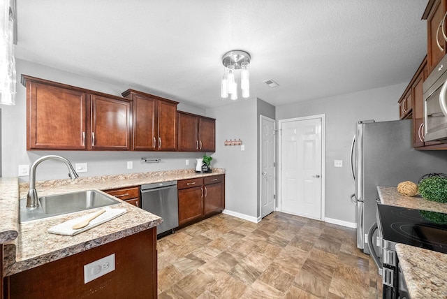 kitchen featuring sink, light stone counters, and stainless steel appliances