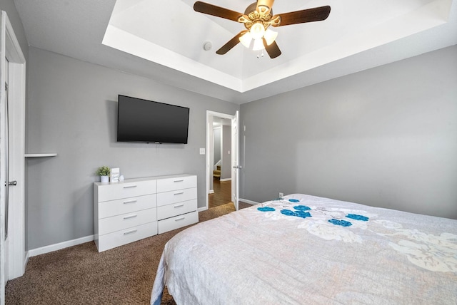 carpeted bedroom with ceiling fan and a tray ceiling