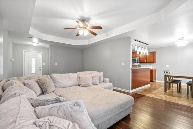 living room with ceiling fan, dark hardwood / wood-style flooring, and a raised ceiling