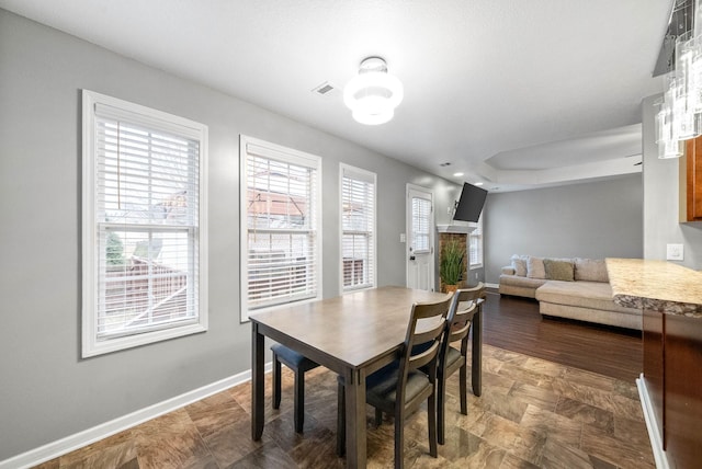 dining area with a raised ceiling and a fireplace