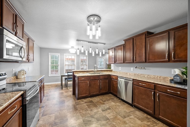 kitchen with kitchen peninsula, sink, hanging light fixtures, stainless steel appliances, and light stone counters