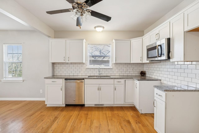 kitchen with tasteful backsplash, sink, stainless steel appliances, and white cabinetry