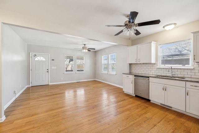 kitchen featuring white cabinetry, decorative backsplash, light wood-type flooring, stainless steel dishwasher, and sink