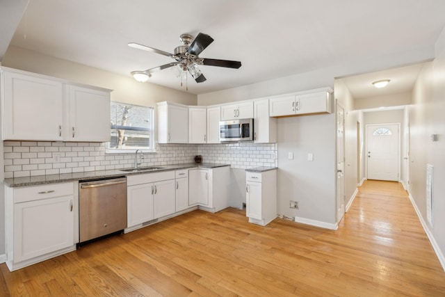 kitchen featuring white cabinets, backsplash, appliances with stainless steel finishes, and sink