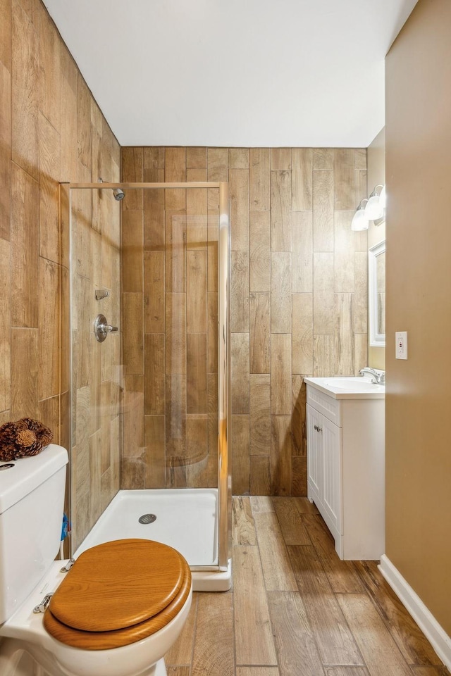 bathroom with toilet, a shower with shower door, hardwood / wood-style floors, and vanity